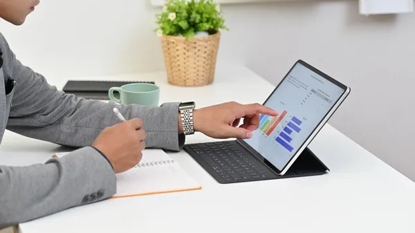 Un empresario analiza gráficos en una tablet, desarrollando una estrategia sobre cómo aumentar las ventas en mi negocio.
