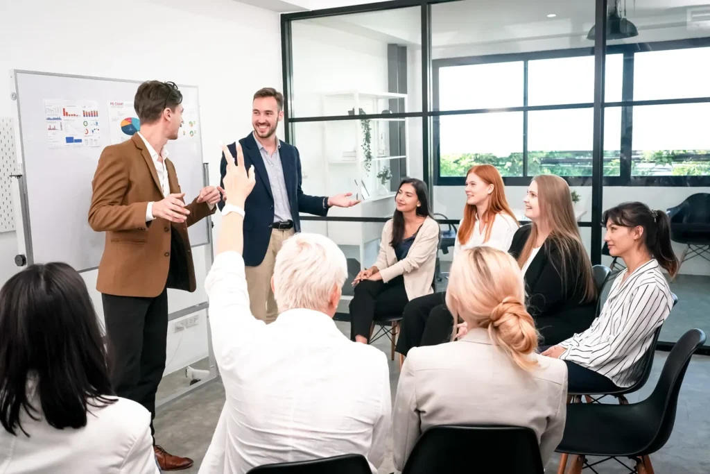 Un hombre de negocios pregunta en una sesión de Empresas de coaching empresarial en México frente a un rotafolio con gráficos.