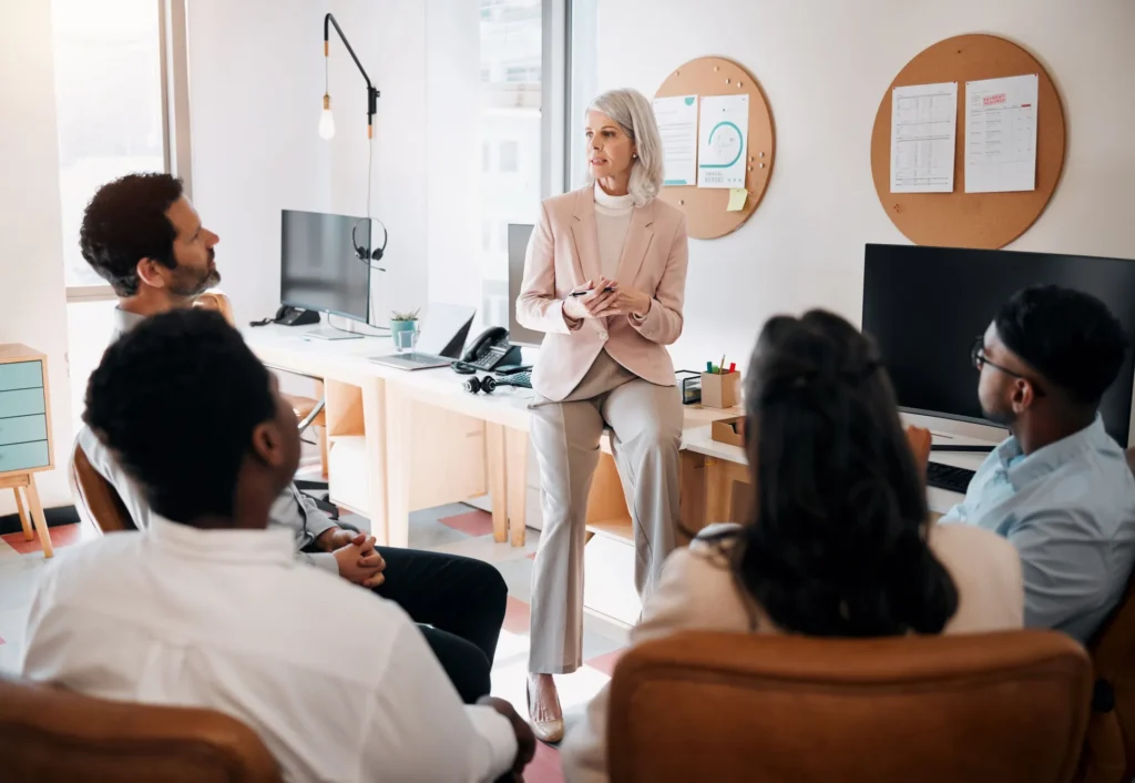 Una coach certificada dirige una capacitación a un equipo diverso en oficinas de Empresas de coaching empresarial en México.